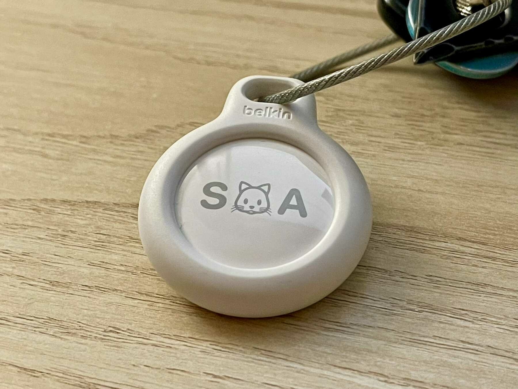 An Apple AirTag in a Belkin keychain holder on a keyring sitting on a desk.